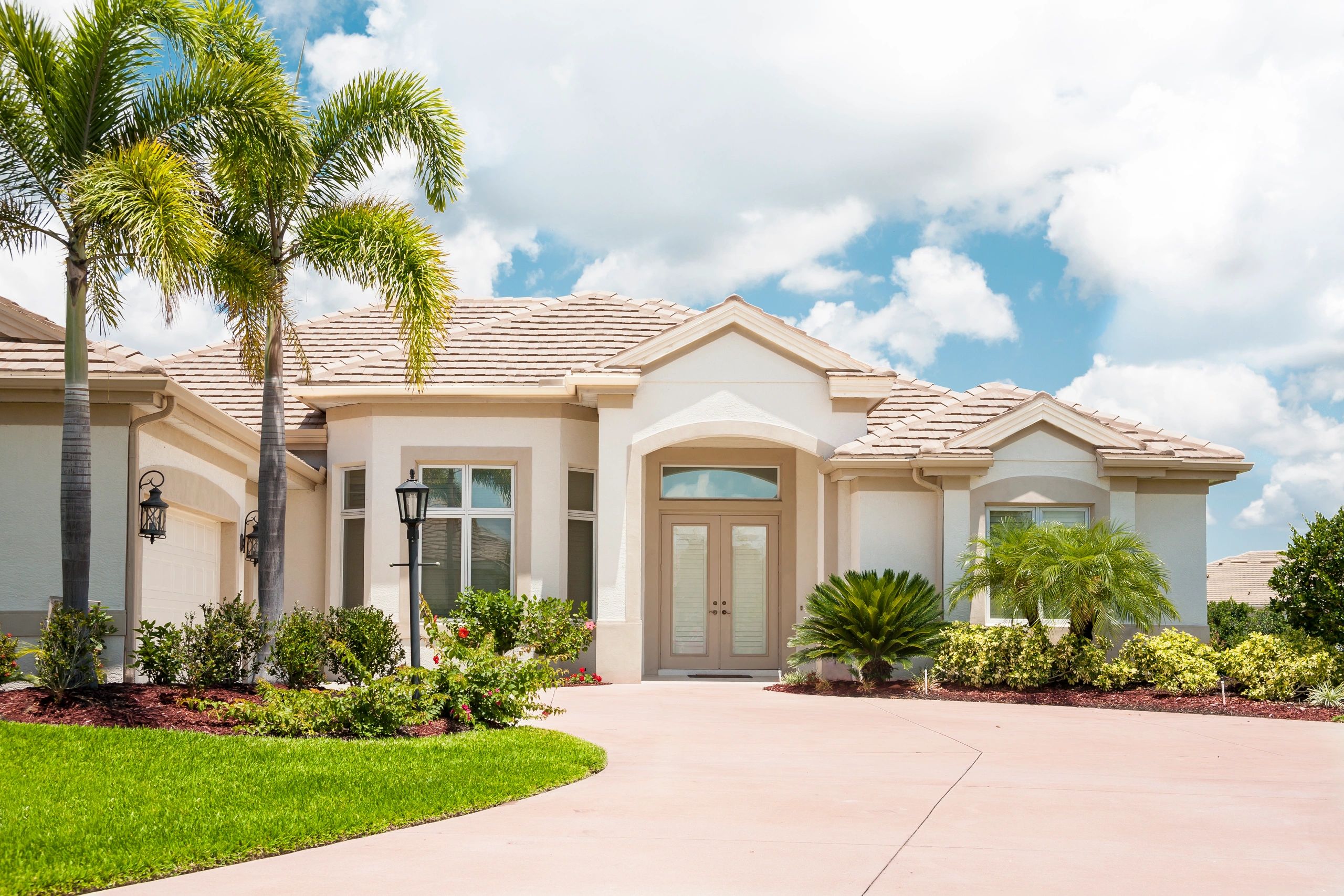 Beautiful new home in the tropics; palm trees, tropical foliage, wide driveway.